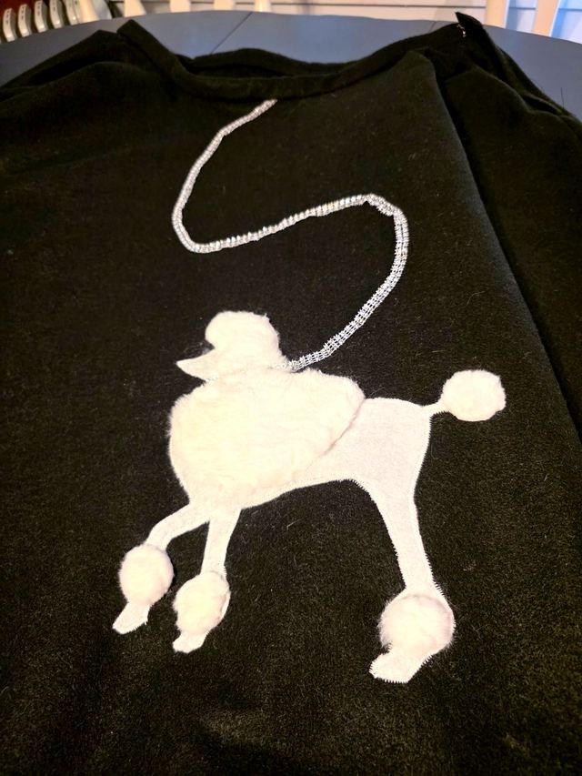 Black circle skirt laid flat with a white poodle applique and a rhinestone leash