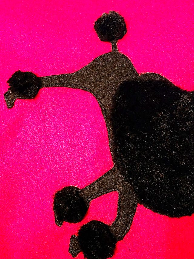Black poodle applique with pom-pom feet on a hot pink skirt