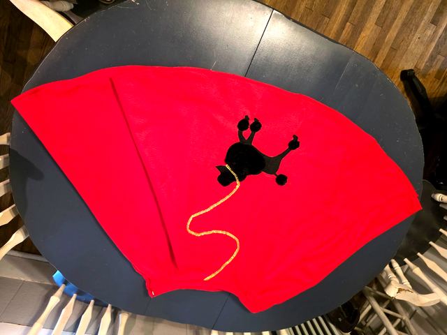 Hot pink circle skirt with a black poodle applique spread out on a table